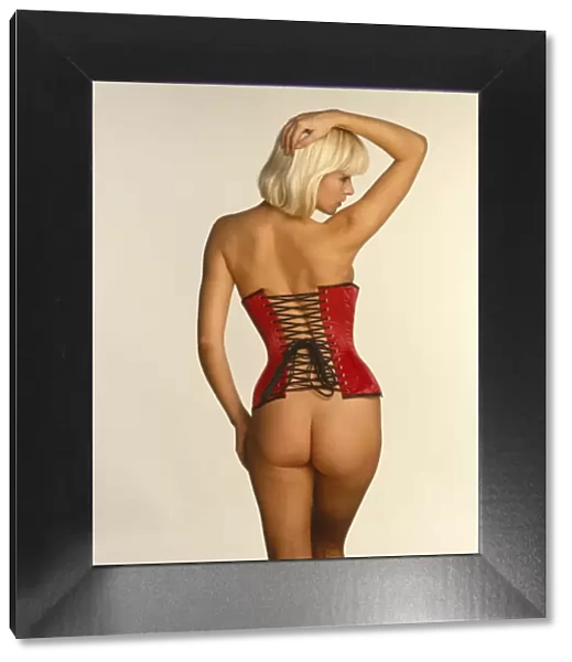Joanne Guest posing in a red corset