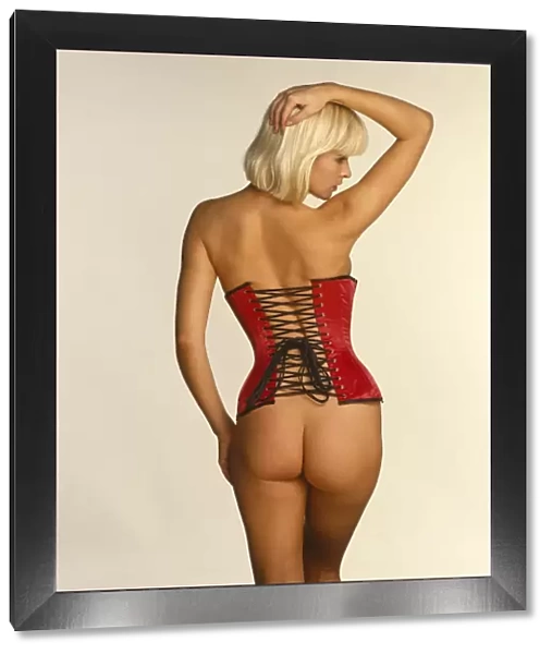 Joanne Guest posing in a red corset