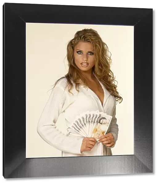 Katie Price, aka Jordan, posing indoors holding a fan of money