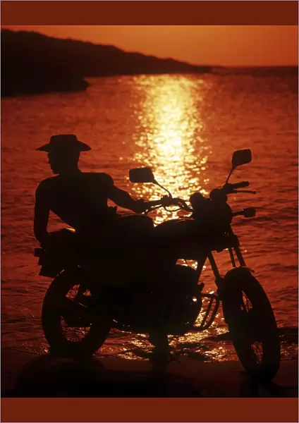 Hunk in profile on a motorbike at sunset