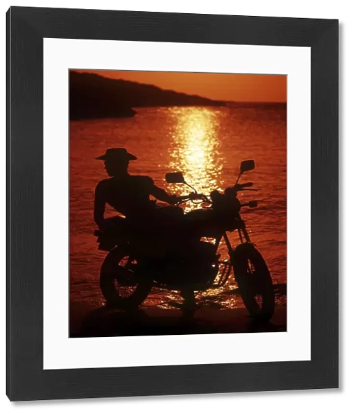 Hunk in profile on a motorbike at sunset