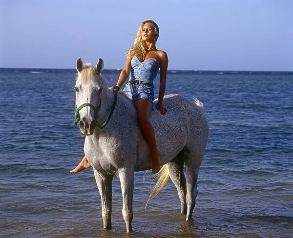 Blonde woman riding a while Horse