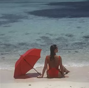 Girl sitting on the beach with red umbrella