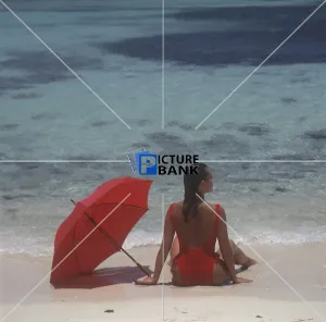 Girl sitting on the beach with red umbrella