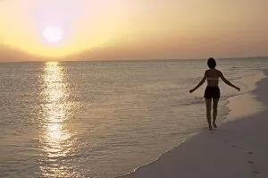 Holiday Scenes Gallery: Girl walking on the beach at sunset in the Maldives